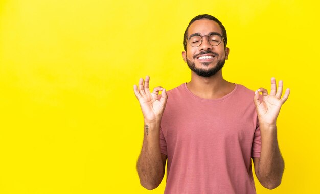 Jovem latino isolado em um fundo amarelo em pose zen