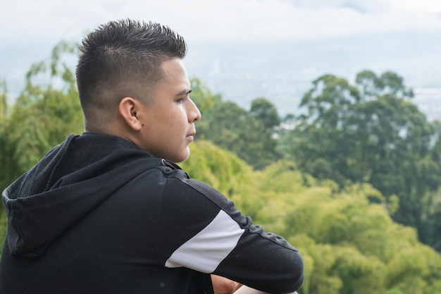 jovem latino no topo de uma montanha meditando sobre sua vida e observando a bela natureza