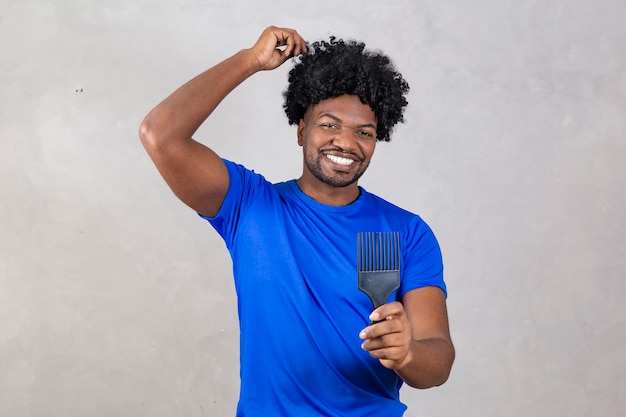 Jovem latino penteando o cabelo garfo para pentear o cabelo encaracolado fundo cinza