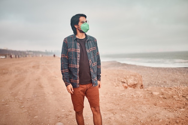 Foto jovem latino posa caminhando na areia durante um belo pôr do sol