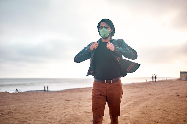 Foto jovem latino posa caminhando na areia durante um belo pôr do sol