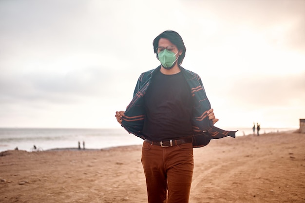 Foto jovem latino posa caminhando na areia durante um belo pôr do sol