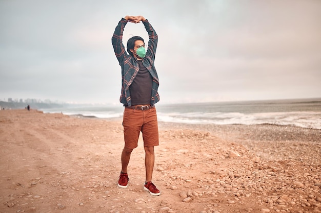 Foto jovem latino posa caminhando na areia durante um belo pôr do sol