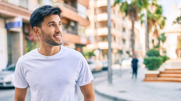 Jovem latino sorrindo feliz andando na cidade