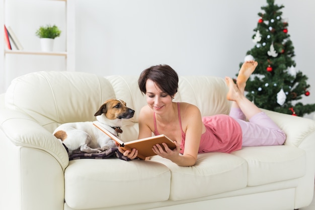 Jovem lendo livro em casa perto da árvore de Natal