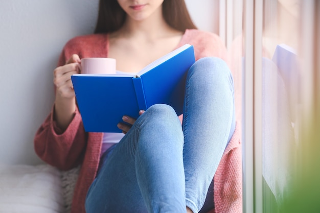 Jovem lendo livro em casa