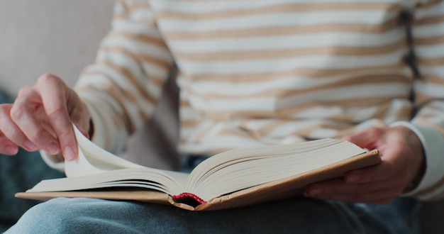 Jovem lendo livro na aconchegante sala de estar virando página aprendendo estudando educação lendo livros fique em casa conceito