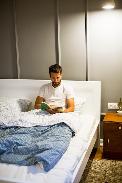 Jovem lendo livro na cama