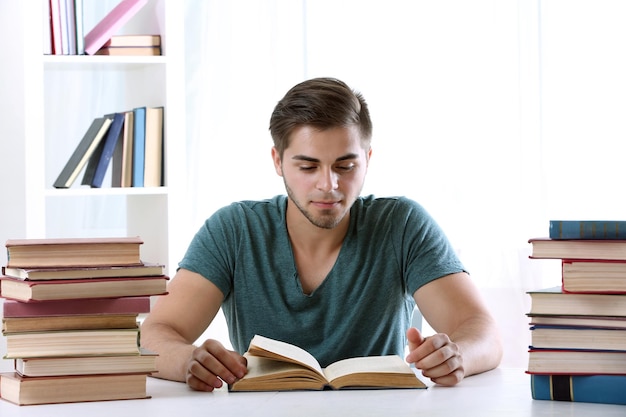 Jovem lendo livro na mesa no quarto