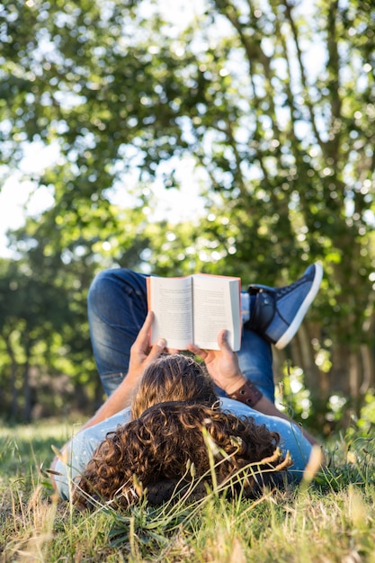 Foto jovem lendo livro no parque