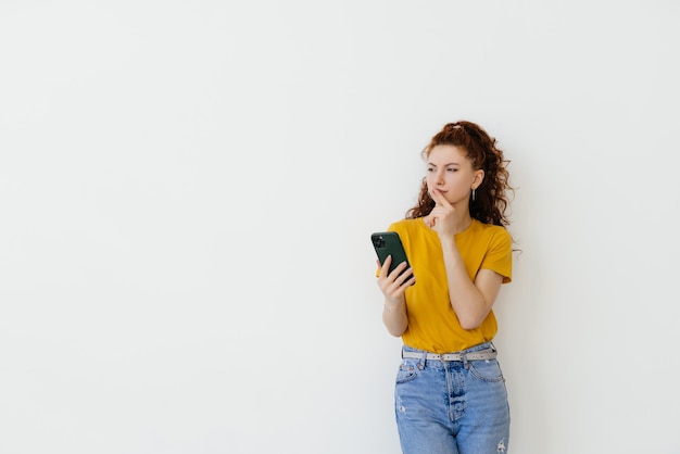 Foto jovem lendo mensagem no smartphone e sorrindo em rede social enquanto está sobre fundo branco