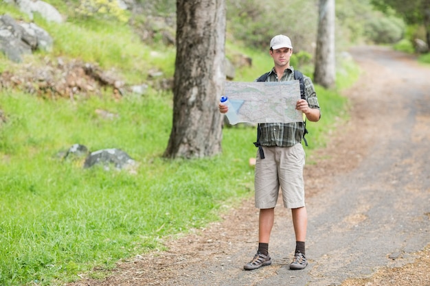 Jovem lendo o mapa na trilha na floresta