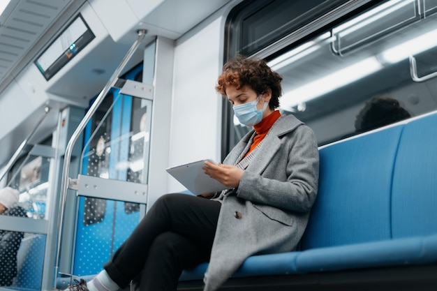 Jovem lendo um ebook enquanto está sentado em um vagão de metrô