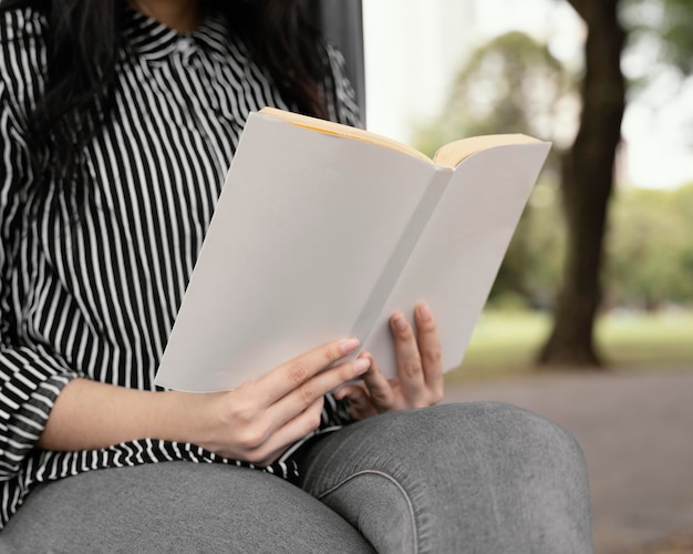 Foto jovem lendo um livro interessante ao ar livre