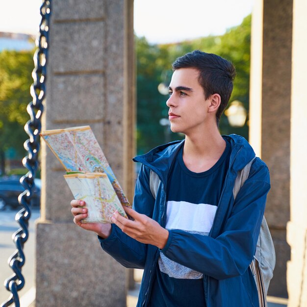 Foto jovem lendo um mapa enquanto está de pé na cidade