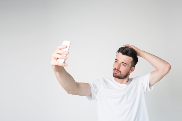 Jovem leva selfie usando o smartphone na mão