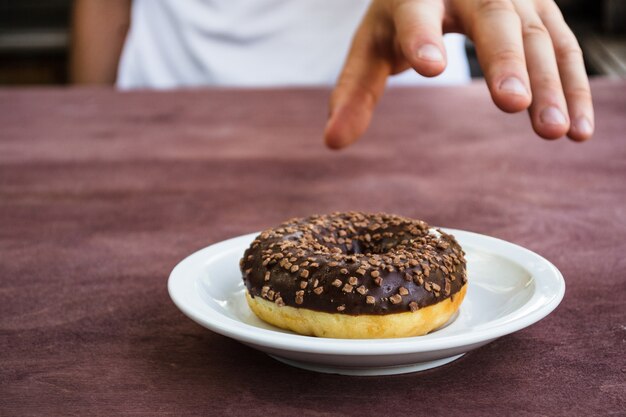 Foto jovem leva um donut de um prato