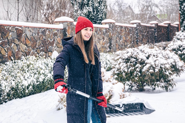 Jovem limpa a neve no quintal em um clima de neve