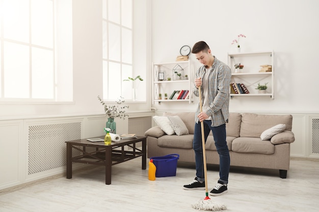 Jovem, limpando a casa com esfregão e detergentes. Conceito de arrumação, limpeza de primavera e arrumação, espaço de cópia