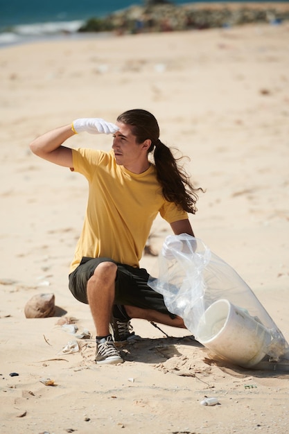 Jovem limpando praia