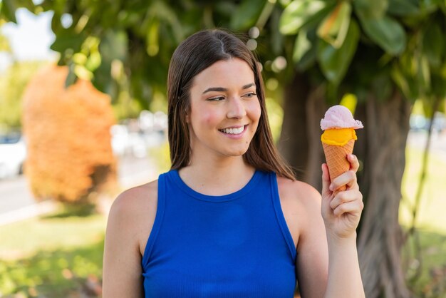 Jovem linda brasileira com um sorvete de corneta ao ar livre com expressão feliz