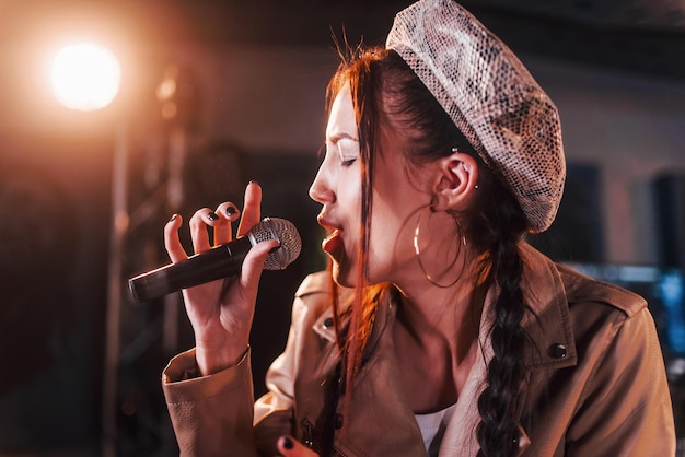 Jovem linda cantora ensaiando em um estúdio de gravação