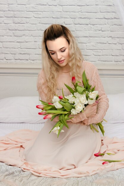 Jovem linda com flores em um vestido longo no hotel