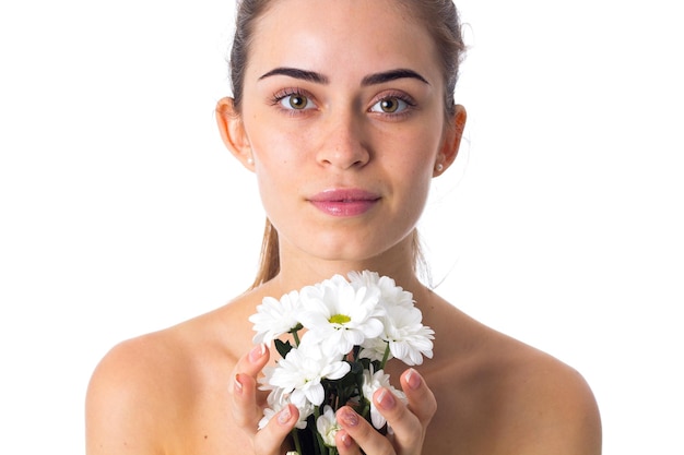 Jovem linda com rabo de cavalo marrom longo segurando flores brancas sobre fundo branco no estúdio