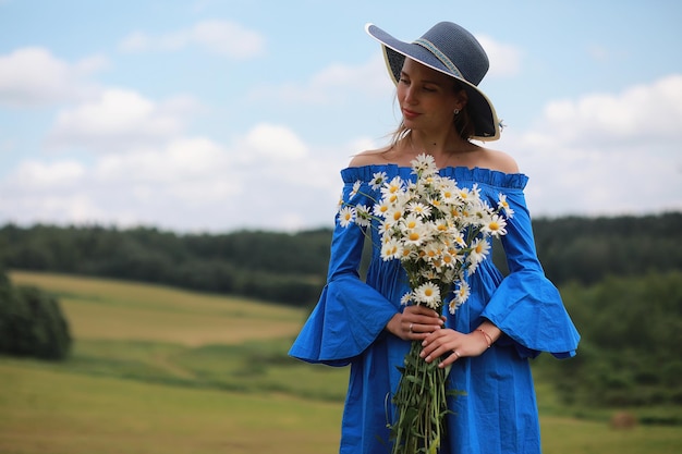 Jovem linda com um chapéu no campo de uma vila ao pôr do sol