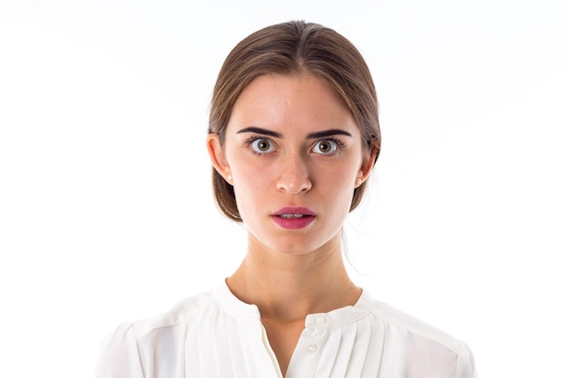 Jovem linda de blusa branca parecendo assustada e assustada em fundo branco no estúdio