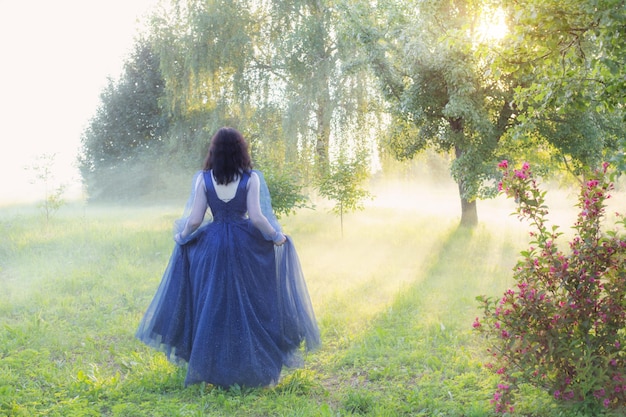 Jovem linda de vestido azul vintage na floresta mágica