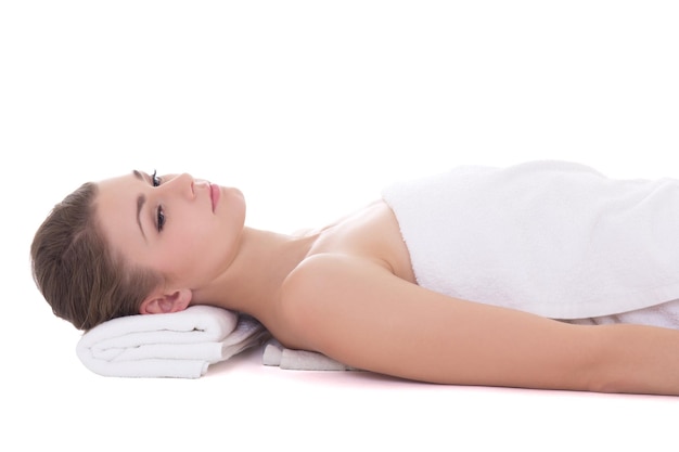 Jovem linda deitada em uma mesa de massagem isolada no fundo branco
