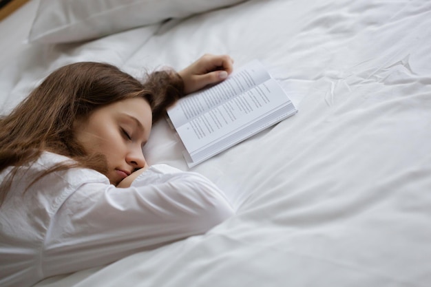 Jovem linda dormindo no livro que ela leu