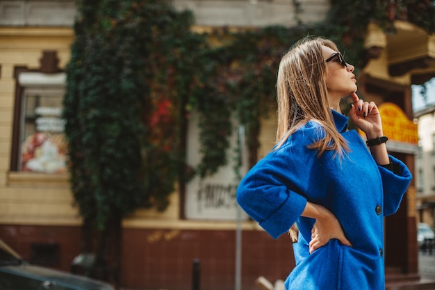 Jovem linda e estilosa andando na rua na tendência da moda outono de casaco azul