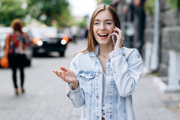 Jovem linda e sorridente caucasiana de cabelos lisos vestindo roupas casuais se sentindo feliz do lado de fora Mulher viajando para o exterior conversando no celular