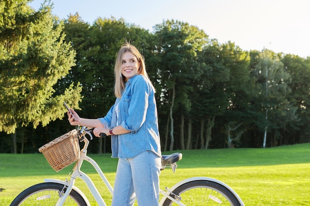 Jovem linda em bicicleta vintage com passeios de cesta na natureza