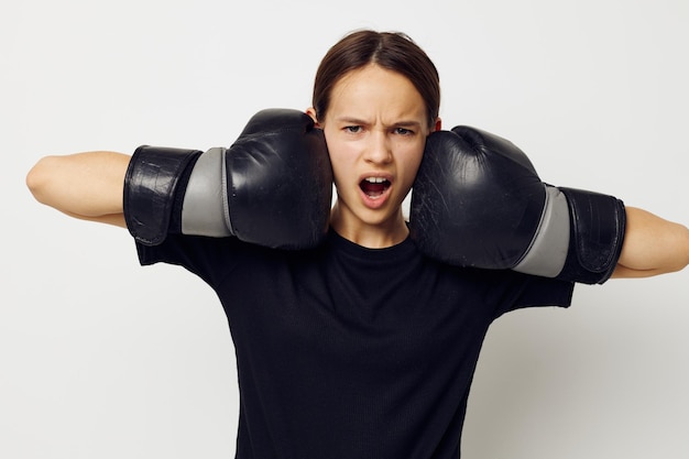 Jovem linda em luvas de boxe em calças pretas e um fundo leve de camiseta