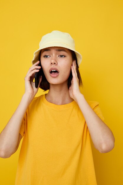 Jovem linda em um estilo juvenil de chapéu amarelo casual falando ao telefone fundo isolado