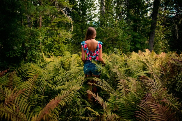 Jovem linda em uma samambaia em uma floresta de verão