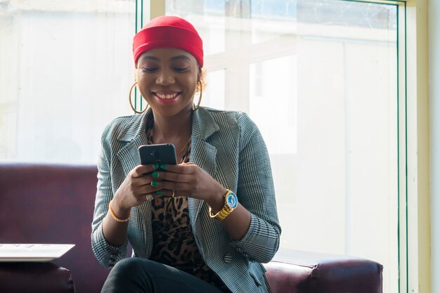 Jovem linda empresária africana se sente animada enquanto opera o celular.