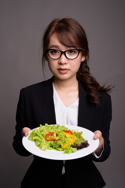 Jovem linda empresária asiática séria segurando salada
