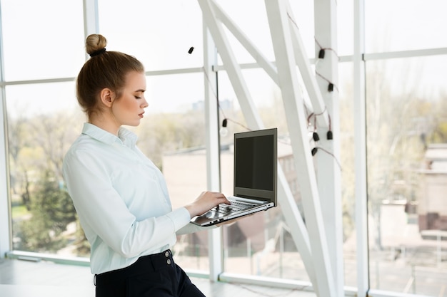 Jovem linda empresária trabalha no escritório com um laptop. Conceito de sucesso