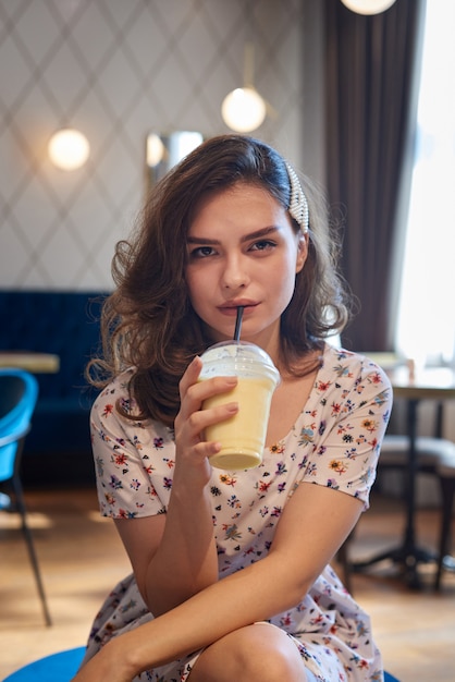 Jovem linda garota de vestido bebendo milk-shake