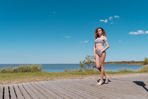 Jovem linda garota latina em traje de banho andando na praia