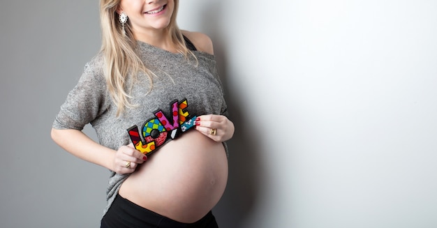 Jovem linda grávida em fundo neutro