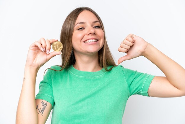 Jovem linda loira segurando um Bitcoin isolado no fundo branco orgulhoso e satisfeito