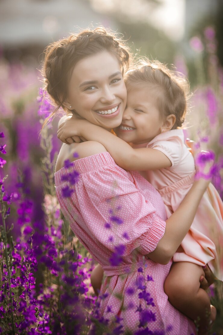 Jovem linda mãe e sua filha ao ar livre com flores. Campo de flores violeta