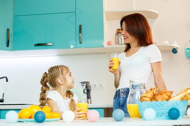 Jovem linda mãe e sua filha brincando na cozinha durante o café da manhã em casa.