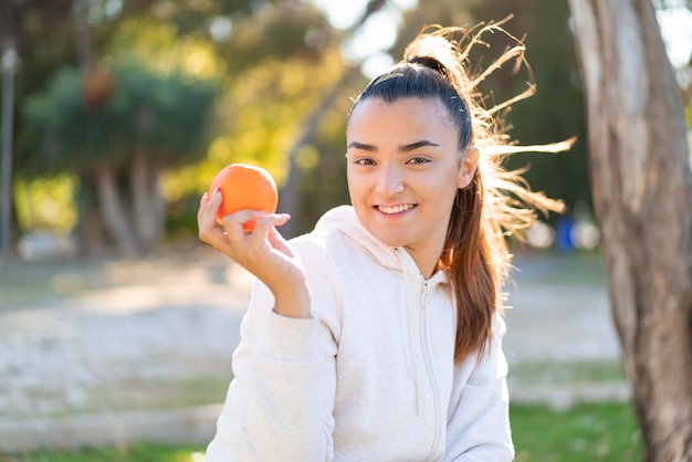 Jovem linda morena segurando uma laranja