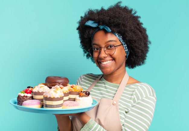 Jovem, linda mulher afro, padeiro com bolos